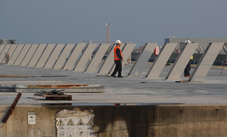 A worker stands on the construction site of the project in Venice, Italy, Friday, Nov. 29, 2019. The system of moveable under water barriers, dubbed Moses, has been beset by corruption, cost overruns and delays. Projected at 1.8 billion euros and to be completed by 2011, the project has cost 5.5 billion euros and won’t be operational before the end of 2021. (AP Photo/Antonio Calanni)