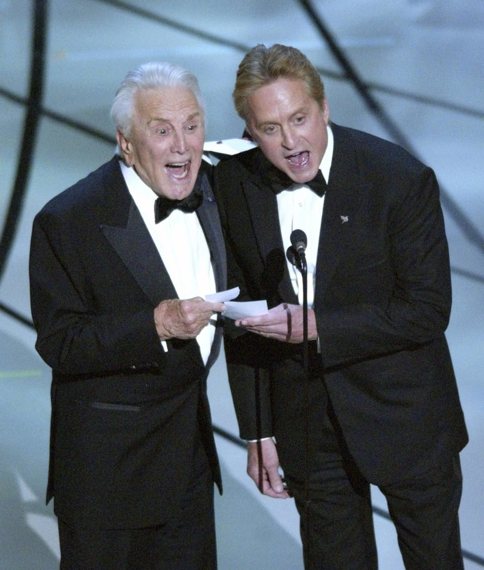 FILE - This March 23, 2003 file photo shows father-son presenters Kirk Douglas, left, and Michael Douglas shouting out "Chicago" as the best picture of the year at the 75th annual Academy Awards in Los Angeles. Kirk Douglas died Wednesday, Feb. 5, 2020 at age 103. The film starred Michael Douglas' wife Catherine Zeta-Jones, who also won the Oscar for best supporting actress. (AP Photo/Kevork Djansezian, File)