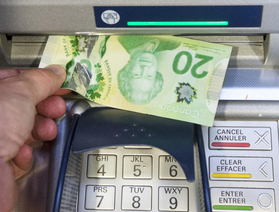 Money is removed from an ATM. THE CANADIAN PRESS/Ryan Remiorz