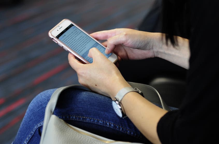A person uses their smartphone at an airport.