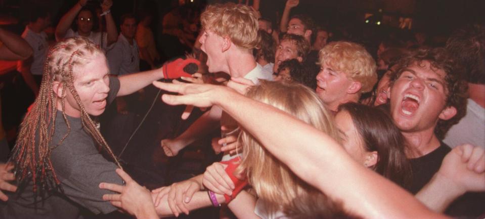 Man with long braids and microphone singing into crowd