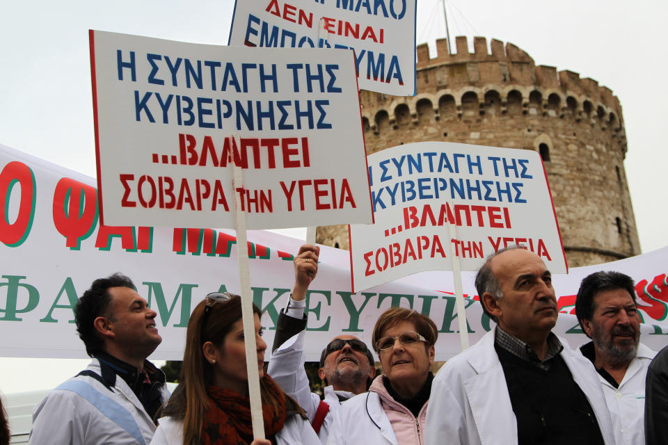 Pharmacists hold up placards reading "government recipe seriously damages health" during a demonstration in the northern port city of Thessaloniki, Greece, Thursday, March 27, 2014. Greece's pharmacies are closed indefinitely in protest at a deal between the Greek government and bailout lenders to deregulate pharmacy store licenses. (AP Photo/Nikolas Giakoumidis)