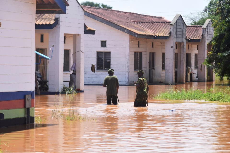 Police officers walk through a flooded compound within the Gamba Police station, Garsen, Kenya, after heavy floods following heavy rains on December 2, 2023.