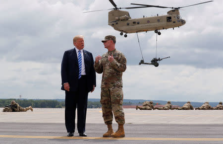 U.S. President Donald Trump talks with U.S. Army Major General Walter “Walt” Piatt, the Commanding General of the Army's 10th Mountain Division and Fort Drum as the president observes a demonstration with troops and a helicopter carrying an artillery piece at Fort Drum, New York, U.S., August 13, 2018. REUTERS/Carlos Barria