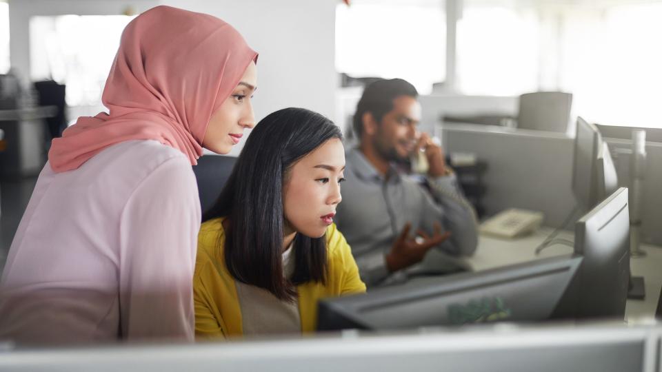 Businesswomen discussing over desktop PC in office.