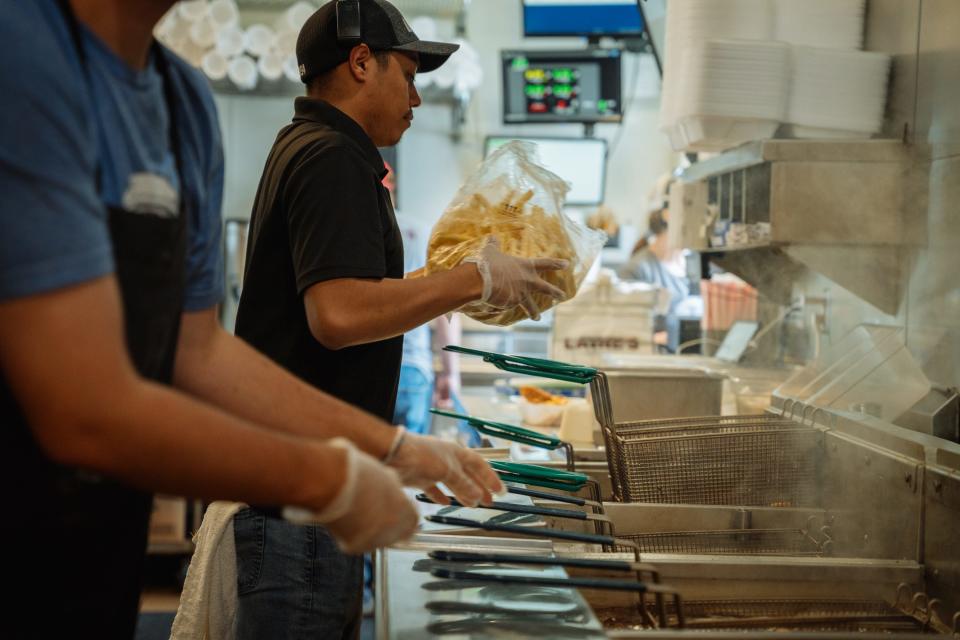 A fast-food worker prepares fries for the deep-fat fryer in a restaurant kitchen.