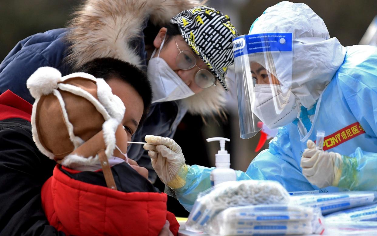 Medical staff take a swab from a child near a residential area in Shijiazhuang  - Wang Xiao/Xinhua via AP