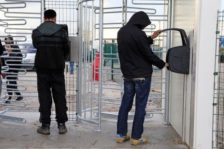 Migrants enter a digital code and use hand prints technology to enter into the area where shipping containers are used as temporary housing near the "jungle", in Calais, northern France, February 24, 2016. REUTERS/Pascal Rossignol