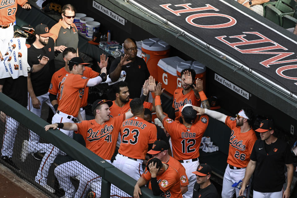 Baltimore Orioles' Rougned Odor (12) is greeted by teammates after scoring a run on a single by Jorge Mateo against Pittsburgh Pirates starting pitcher JT Brubaker during the second inning of a baseball game, Saturday, Aug 6, 2022, in Baltimore. (AP Photo/Terrance Williams)