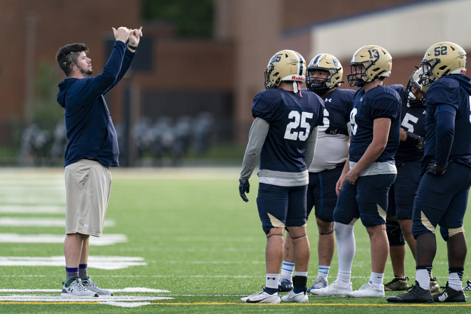 Gallaudet assistant coach Shelby Bean, left, coaches players during football practice at Hotchkiss Field, Tuesday, Oct. 10, 2023, in Washington. As a Deaf football player for four years at Gallaudet, Bean called defensive plays with American Sign Language and dealt with other obstacles hearing opponents would never need to worry about. Now he was on the sideline earlier this month when a new football helmet the school developed with AT&T allowed the plays to be displayed visually inside quarterback Brandon Washington's helmet. (AP Photo/Stephanie Scarbrough)