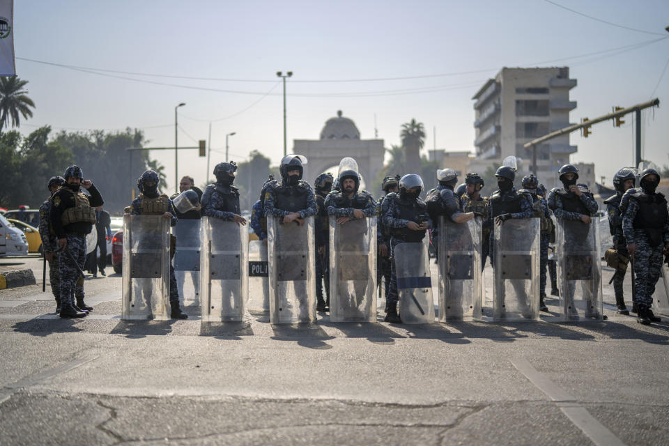 Riot police take position on the outskirts of the Green Zone as pensioners, some of whom were prisoners of war during the first Gulf War, demonstrate in Baghdad, Iraq, Monday, Feb. 27, 2023. A U.S.-led war two decades earlier deposed a dictator whose imprisonment, torture and execution of dissenters had kept 20 million people living in fear for a quarter of a century. But it also broke what had been a unified state at the heart of the Arab world. (AP Photo/Jerome Delay)