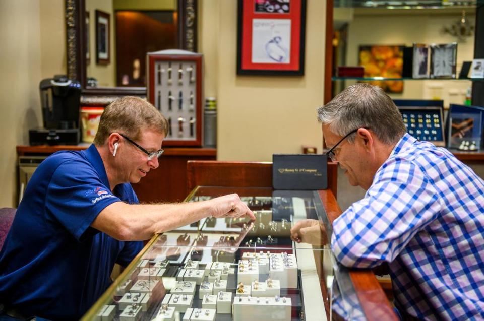 Dan Standley, left, of Roseville, points to jewelry as Dan Barrett, employee of Kenny G & Company Fine Jewelers, reaches into a case in Roseville on Monday, May 18. There were no masks Monday at the store, which recently reopened at the Fountains at Roseville shopping center after the state allowed retail stores to operate in Placer County.