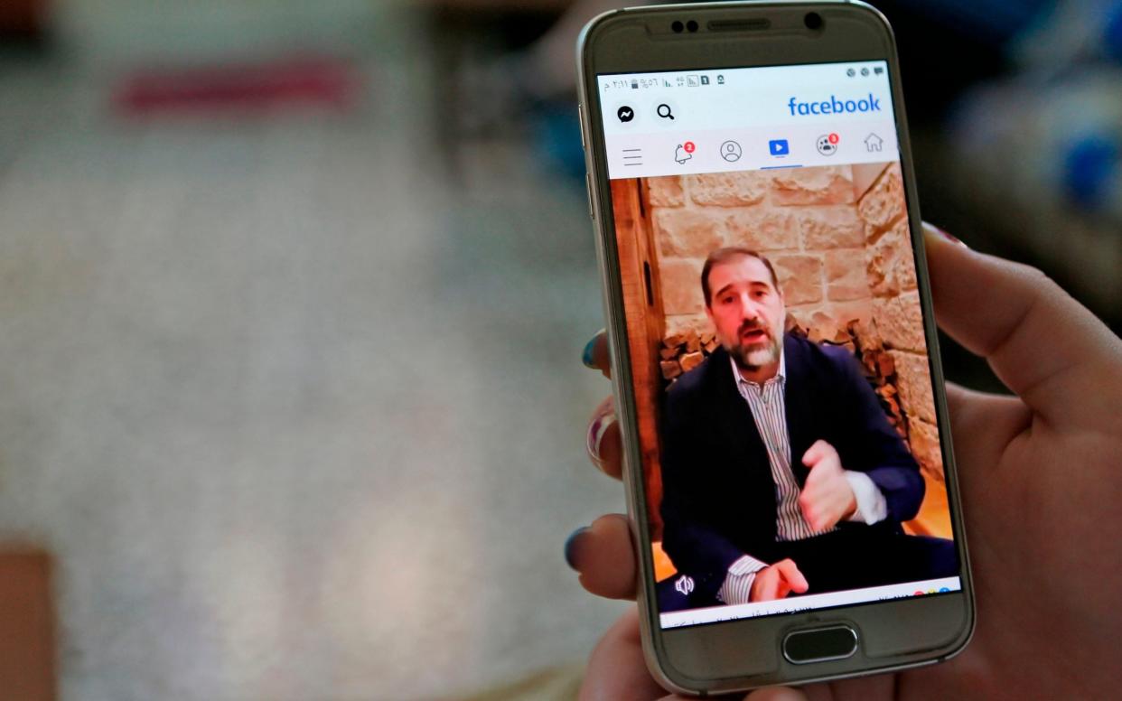 A woman watches the Facebook video of Syrian businessman Rami Makhlouf on her mobile in Syria's capital Damascus - AFP