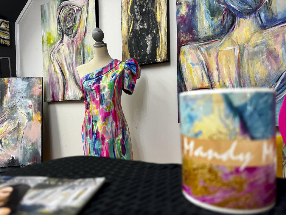 Louisiana artist Mandy Poche's hand-painted dress made to match her painting stands near other artwork at her gallery in Ponchatoula, La., Nov. 1, 2022. (AP Photo/Stephen Smith)