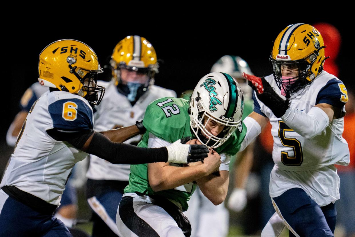 Dublin Coffman's Quinn Hart (12) tries to make his way through Springfield's Javyn Martin (6) and Aaron Scott (5) during Friday night's regional final.