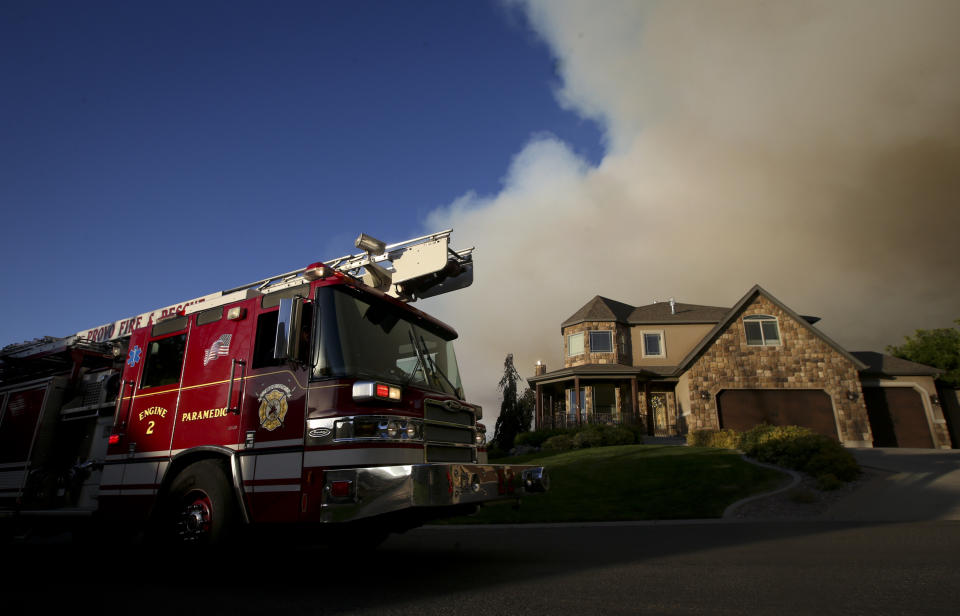 In this Thursday, Sept. 13, 2018, photo a Provo fire engine drives up High Sierra Drive South in Elk Ridge, Utah during a mandatory evacuation. A fast-moving Utah wildfire fanned by high-winds has more than doubled in size as it burns through dry terrain and forces evacuations of hundreds of homes, the U.S. Forest Service said Friday. (Isaac Hale/The Daily Herald via AP)