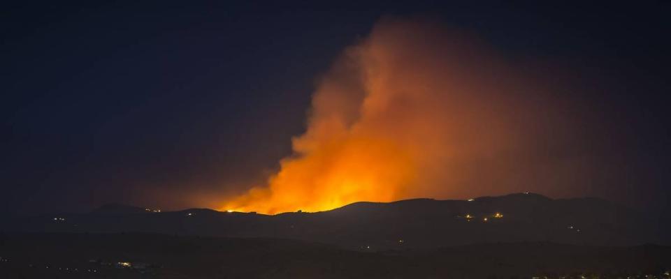 Wildfire burning in the Northern Nevada Hills at night with glow and smoke