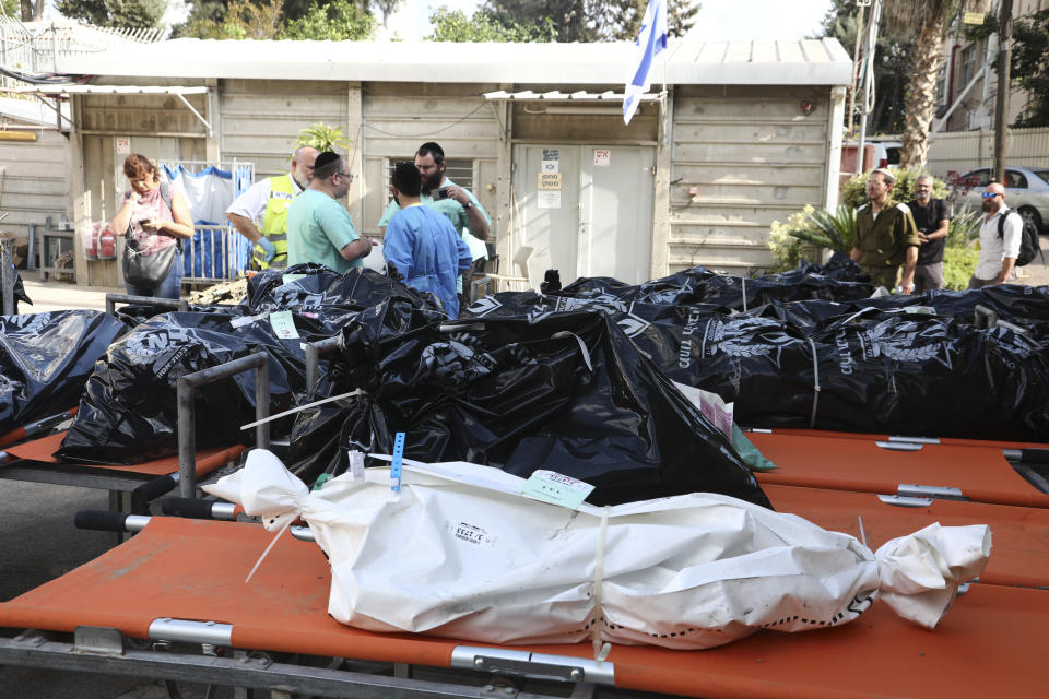 Forensic experts stand next to the bodies of Israelis killed by Hamas militants in the National Center for Forensic Medicine in Tel Aviv, Monday, Oct. 16, 2023. (AP Photo/Gideon Markowicz)