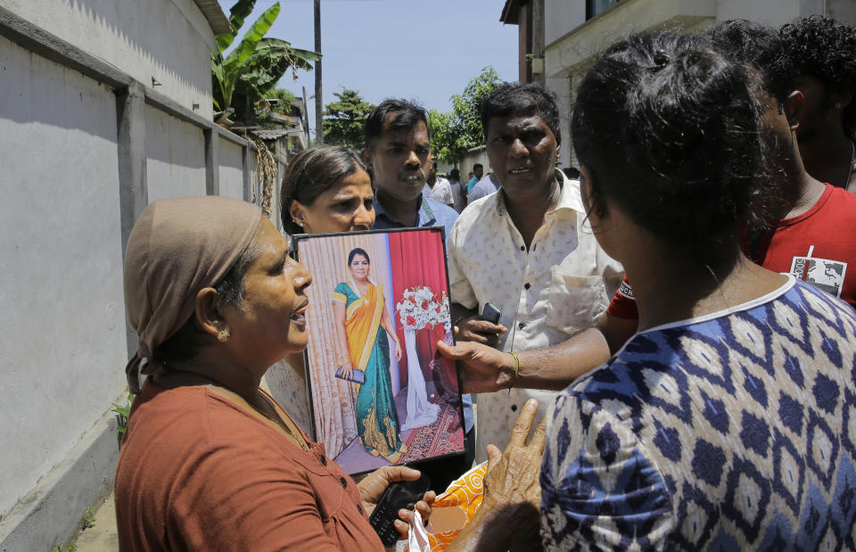 A Sri Lankan woman enquires about her relative holding her photographs outside hospital morgue, a day after the serial blasts in Colombo, Sri Lanka, Monday, April 22, 2019. A government crime investigator says the coordinated Easter bombings that ripped through Sri Lankan churches and luxury hotels were carried out by seven suicide bombers which killed and injured hundreds of people, was Sri Lanka's deadliest violence since a devastating civil war in the South Asian island nation ended a decade ago. (AP Photo/Eranga Jayawardena)