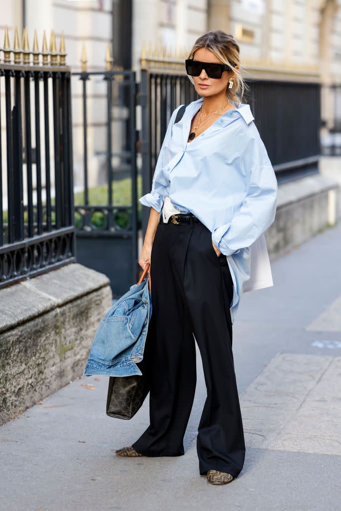 a woman wears a blue button down and black pants