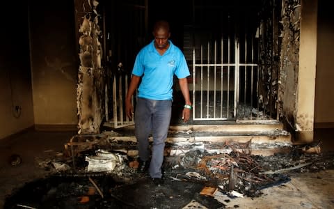 A man walks past fire damage at headquarters of the opposition Movement For Democratic Change (MDC) in Harare - Credit: &nbsp;PHILIMON BULAWAYO/&nbsp;REUTERS