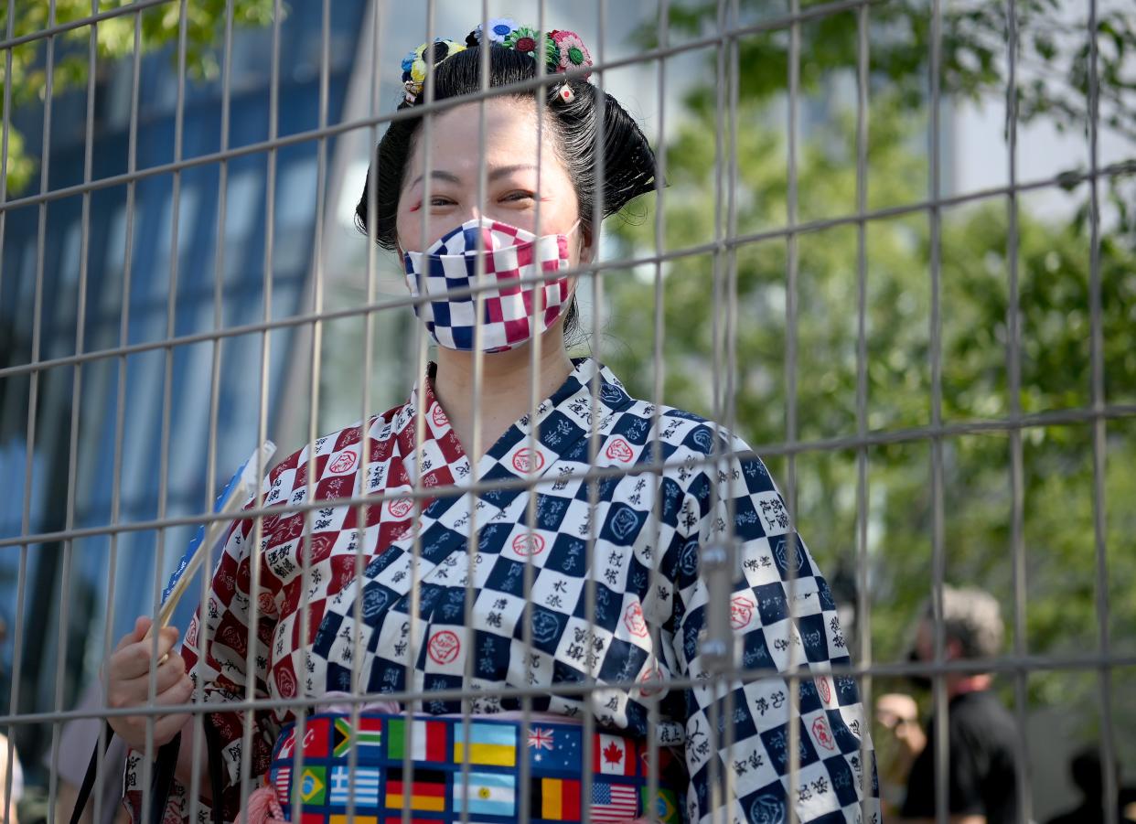 A woman in traditional clothing looks on from behind a fence prior to the Opening Ceremony of the Tokyo 2020 Olympic Games at Olympic Stadium (Getty Images)