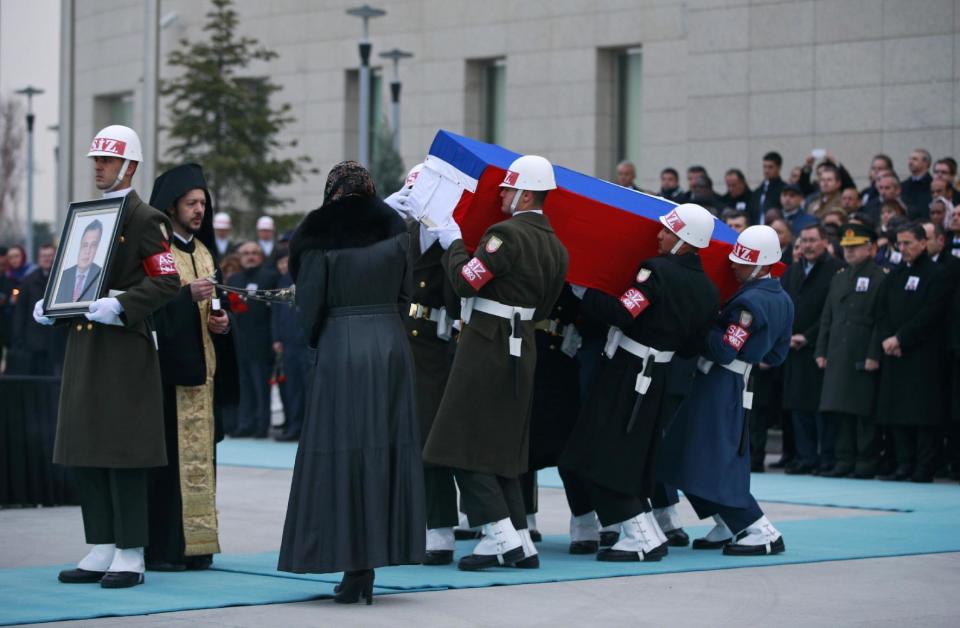 Members of a Turkish forces honour guard carry the Russian flag-draped coffin of Russian Ambassador to Turkey Andrei Karlov who was assassinated Monday, as an officer, left, holds his picture during a ceremony at the airport in Ankara, Turkey, Tuesday, Dec, 20, 2016. Turkey and Russia are more committed than ever to advance peace efforts in Syria, the two countries' foreign ministers declared Tuesday, a day after the killing in an attack both countries described as an attempt to disrupt their improved ties. (AP Photo/Emrah Gurel)