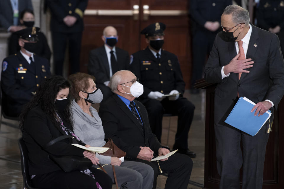 Senate Majority Leader Chuck Schumer of New York, speaks to family during a ceremony memorializing U.S. Capitol Police officer Brian Sicknick, as an urn with his cremated remains lies in honor on a black-draped table at the center of the Capitol Rotunda, Wednesday, Feb. 3, 2021, in Washington.(Brendan Smialowski/Pool via AP)