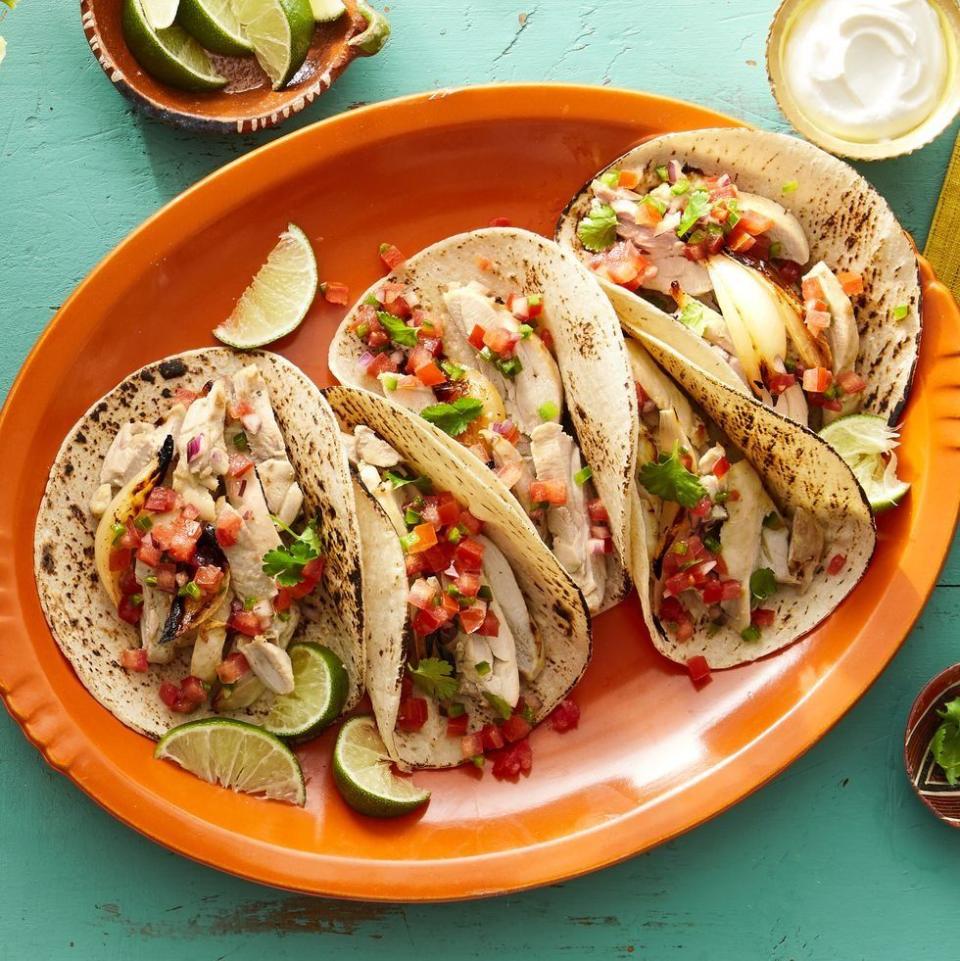 pollo asado tacos on orange platter with limes