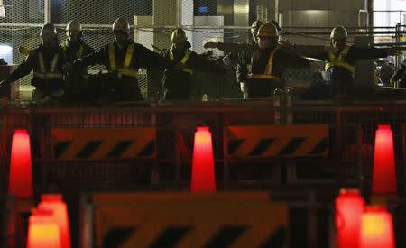 Workers stretch their bodies before they start working at a construction site on a public road in Tokyo in this December 23, 2013 file photo. REUTERS/Yuya Shino/Files