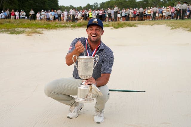 Bryson DeChambeau holds the US Open trophy in a bunker