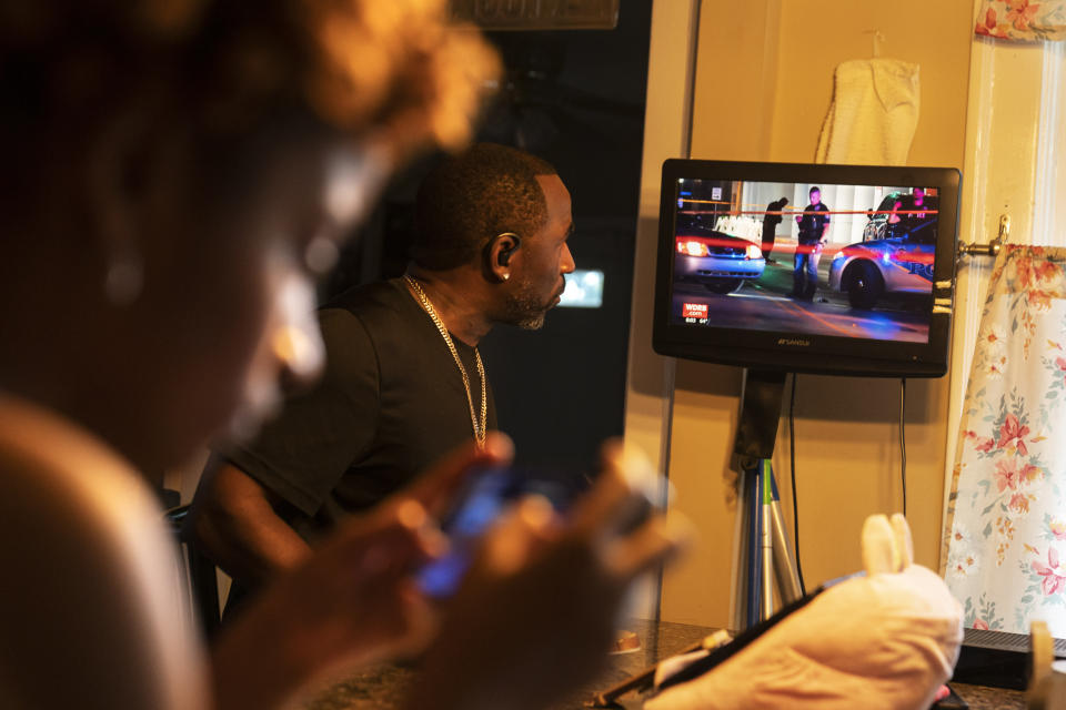 Navada Gwynn, right, watches the news of a recent shooting in the city while eating breakfast with his daughter, also named Navada, 15, at their home in Louisville, Ky, Tuesday, Aug. 29, 2023. The Gwynns are now home schooling Navada, their youngest, to keep her safe. (AP Photo/David Goldman)