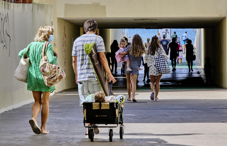 ESTORIL, PORTUGAL - JULY 10: Mask-clad beachgoers cart their baby as they arrive in Praia das Poças on a warm and sunny morning during the COVID-19 Coronavirus pandemic on July 10, 2021, in Estoril, Portugal. Sixty of the 278 municipalities in mainland Portugal are, as of today, at high or very high risk of COVID-19 incidence, 15 more than last week, and being subject to more restrictive measures, including curfews at night. The Council of Ministers decided last July 08 new measures to contain the pandemic at a time when the Portuguese vacations period intensifies. Locals and tourists have to present a negative test or digital certificate to access tourist establishments and local accommodation in continental Portugal, and they will have to do the same to be in the interior of restaurants on Fridays from 19.00 hours and throughout the day on Saturdays, Sundays and holidays in municipalities with high and very high risk. Non compliance of the regulations by those at restaurants and hotels are liable to be fined between 100 and 500 euros and establishment owners will be subjected to fines between 1,000 and 10,000 euros. (Photo by Horacio Villalobos#Corbis/Corbis via Getty Images)