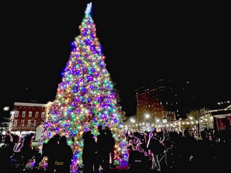 Festivalgoers take photos next to Erie's 35-foot-tall Christmas tree adorned with more than 4,800 colored LED lights, during the 2022 Downtown D'Lights event in Perry Square.