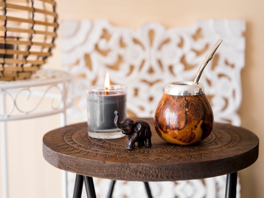 engraved wood side table with elephant statue, drink, and candle