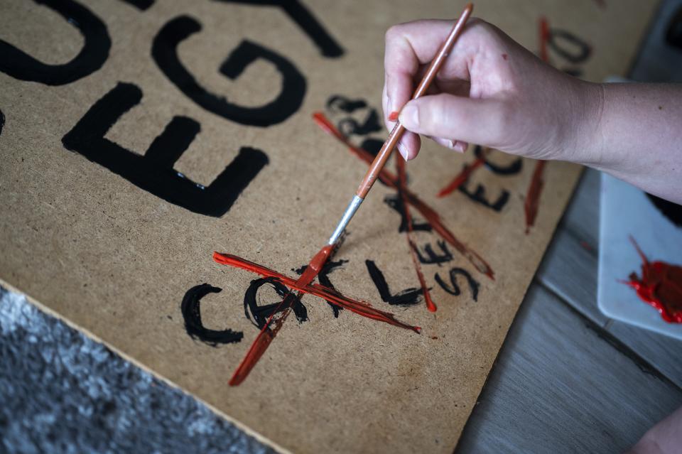 A woman paints a banner for a demonstration against a factory to produce batteries for electric vehicles built by China-based Contemporary Amperex Technology Co. Limited (CATL) on Tuesday, May 23, 2023, near Debrecen, Hungary. Residents, environmentalists and opposition politicians are worried that the factory will exacerbate existing environmental problems and use up the country's precious water supplies. (AP Photo/Denes Erdos)