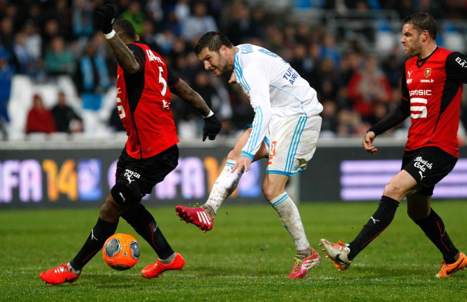 Marseille's French forward Andre-Pierre Gignac, center, challenges for the ball with Rennes'French defender Jean Armel Kana-Biyik, left , French miedfielder Romain Alessandrini , during their League One soccer match, at the Velodrome Stadium, in Marseille, southern France, Saturday, March 22, 2014. (AP Photo/Claude Paris)