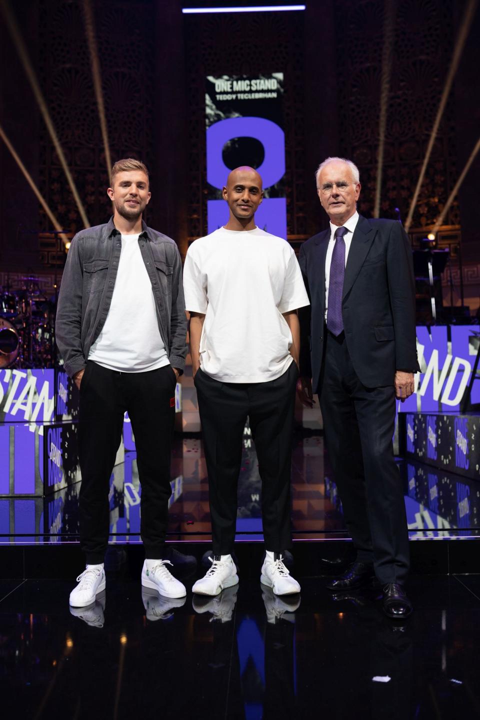 Moderator Teddy Teclebrhan (Mitte) begrüßt in einer der fünf Ausgaben von "One Mic Stand" Fußball-Weltmeister Christoph Kramer (links) und Harald Schmidt. (Bild: Amazon Prime Video / LEONINE Studios / Daniel Dornhöfer)