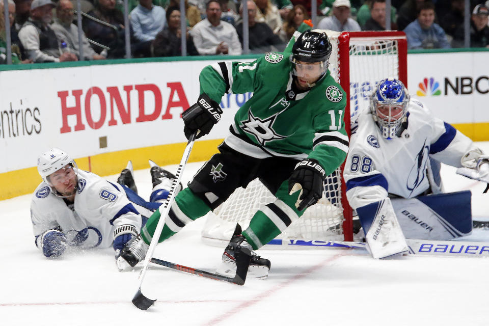 Dallas Stars center Andrew Cogliano, center, is brought down as Tampa Bay Lightning center Tyler Johnson, left, picks up the tripping penalty during the first period of an NHL hockey game in Dallas, Monday, Jan. 27, 2020. (AP Photo/Ray Carlin)