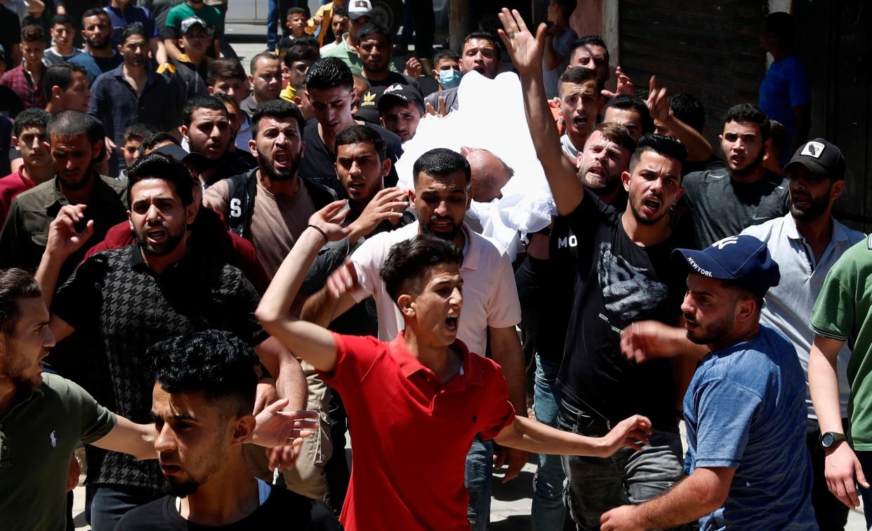 Mourners chant Islamic slogans while carrying the body of Walid Shamaly during a funeral for thirteen Hamas militants outside the mosque in Gaza City, Thursday, May 13, 2021.