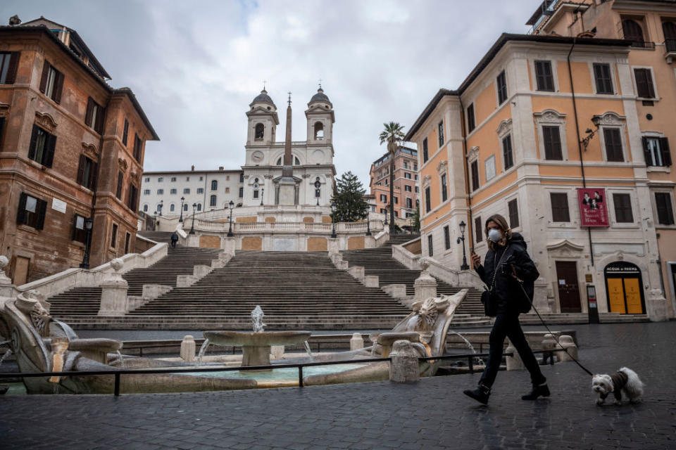 A woman wearing protective mask walks with her dog in Piazza di Spagna (Spagna square) during the Coronavirus emergency in Rome, Italy. 