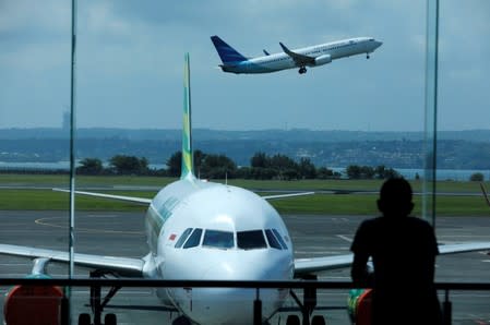 FILE PHOTO: A passenger waiting for his flight to depart watches a plane take off from the domestic terminal at Ngurah Rai International Airport, in Kuta