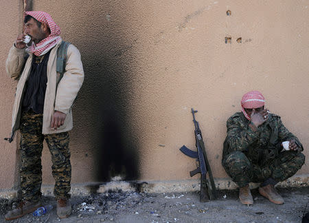 Fighters from the Syrian Democratic Forces (SDF) drink tea in the village of Baghouz, Deir Al Zor province, Syria February 18, 2019. REUTERS/Rodi Said