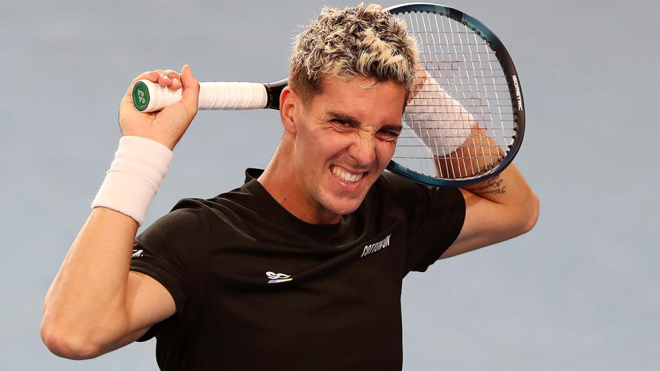 Thanasi Kokkinakis squeezes his racquet behind his head in frustration.