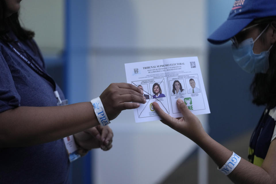 An electoral worker hands over a marked ballot during the vote count for the runoff presidential election, after polls closed, in Guatemala City, Sunday, Aug. 20, 2023. Bernardo Arévalo, of the Seed Movement party, and former first lady Sandra Torres, of the National Unity of Hope party or UNE, are competing to be the country's next president.(AP Photo/Moises Castillo)