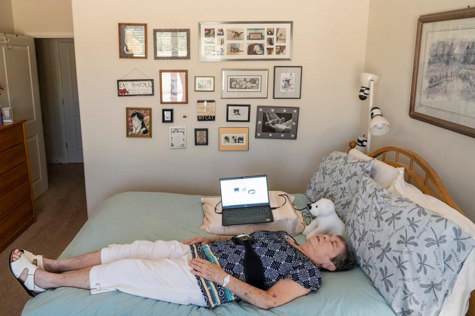 Donna Whitworth demonstrates how she uses her Fire1 device. She rests on her bed with the laptop beside her while she waits for the belt to pick up the data from the Fire1 inside her inferior vena cava and send it to her doctors.