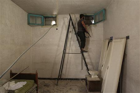 A Free Syrian Army fighter stands on a ladder as he peeks through a hole near Hanano Barracks, which is controlled by forces loyal to Syria's President Bashar al-Assad, in Aleppo September 11, 2013. REUTERS/Muzaffar Salman