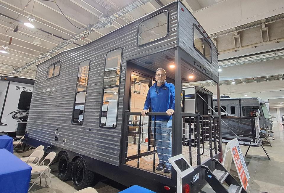 Jason Trettel, general manager of Butler RV Center, stands on the covered rear deck of a camper on display at the 2024 Pittsburgh RV Show. The 16-foot camper includes a sliding patio door and loft area.