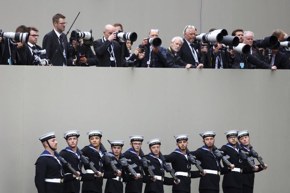 Members of the Royal Navy stand underneath row of phtoographers.