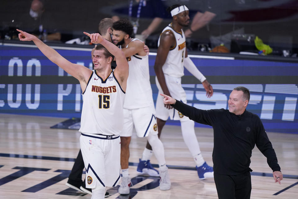 Denver Nuggets center Nikola Jokic (15) and Denver Nuggets head coach Michael Malone, right, celebrates their win over the Los Angeles Clippers in an NBA conference semifinal playoff basketball game Tuesday, Sept. 15, 2020, in Lake Buena Vista, Fla. (AP Photo/Mark J. Terrill)